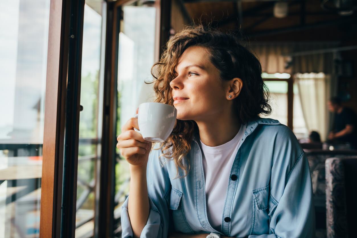 Calm woman drinking from a cup looking out of the window