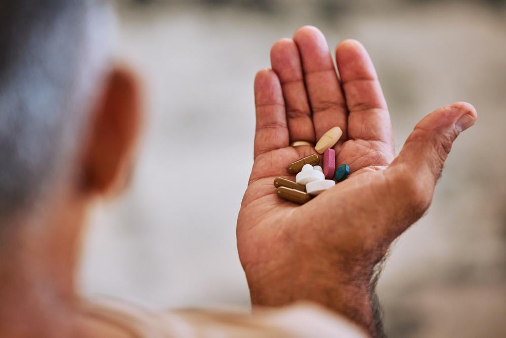 Hand of a senior man holding different pills