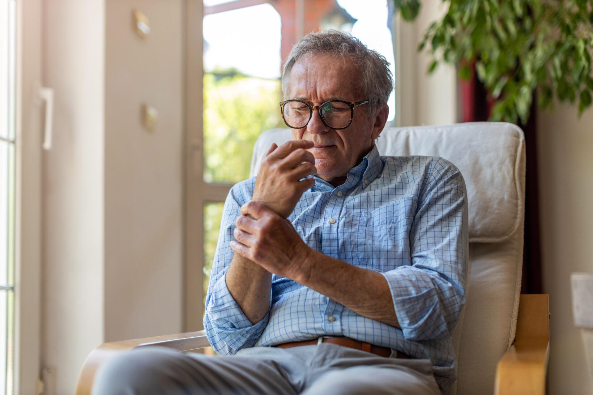 Senior man with arthritis rubbing hands.