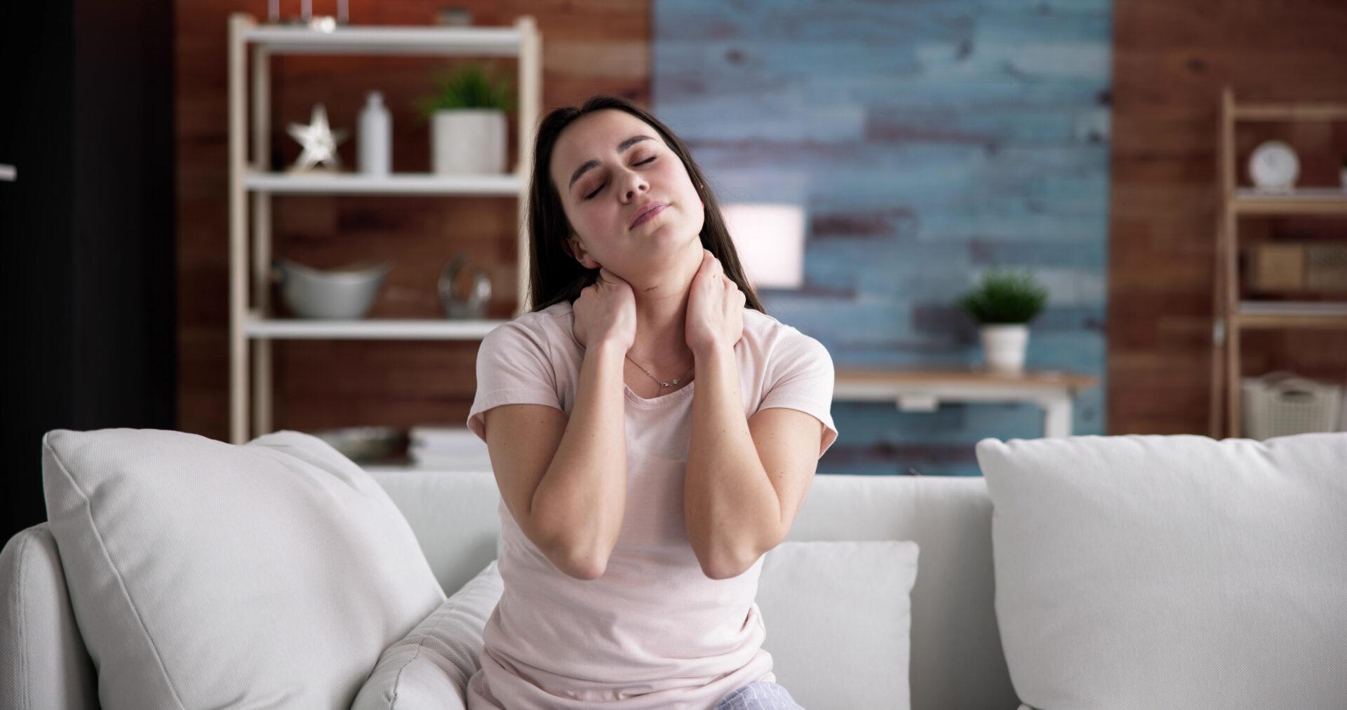 Woman suffering neck pain at home.