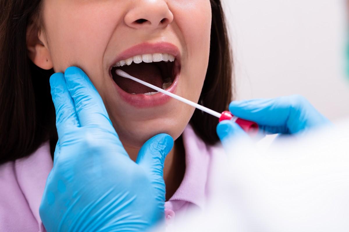 Close-up of a doctor taking a saliva sample from a female.