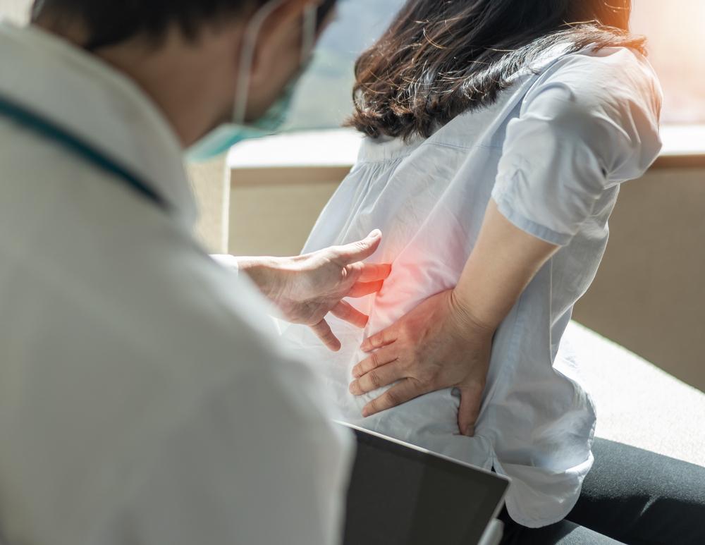 Woman patient with backache seeing an orthopaedic surgical doctor for medical treatment