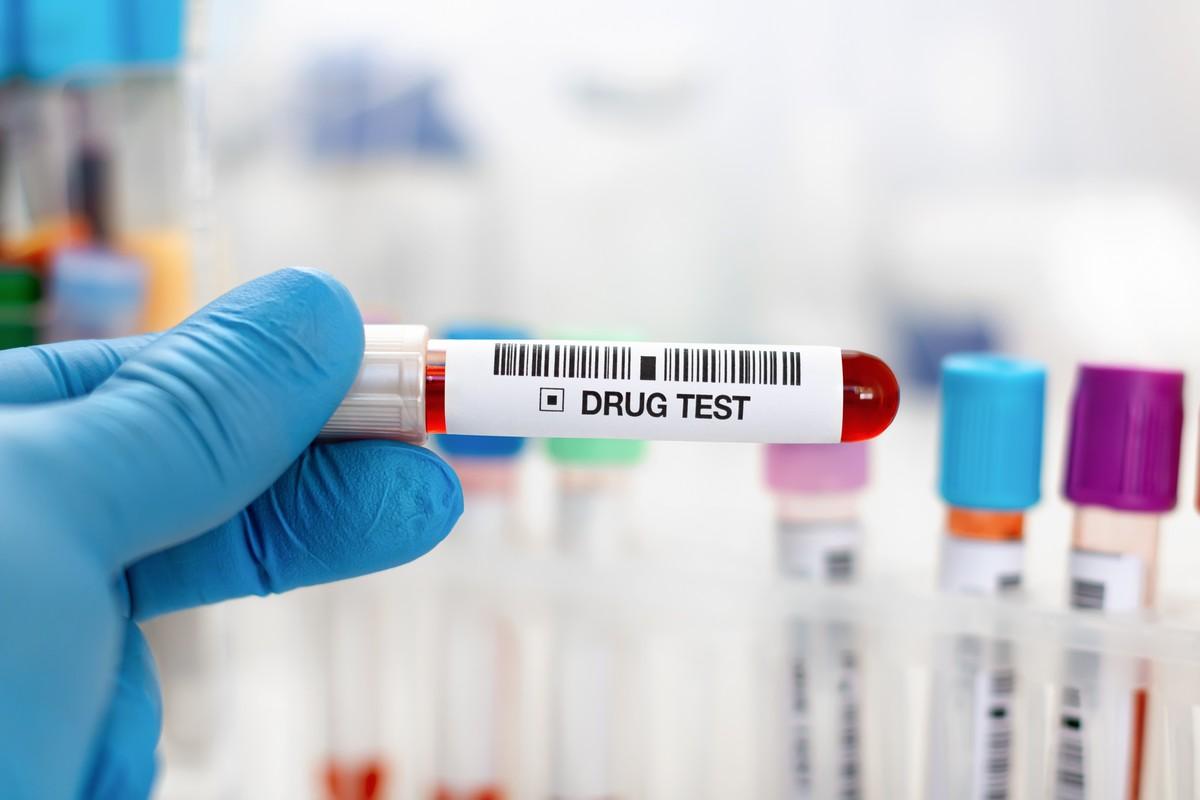 A physician holding a vial of blood for drug analysis.