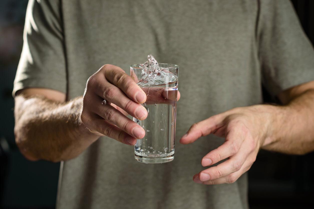 Water splashes from a glass in the hand of a man with tremors.