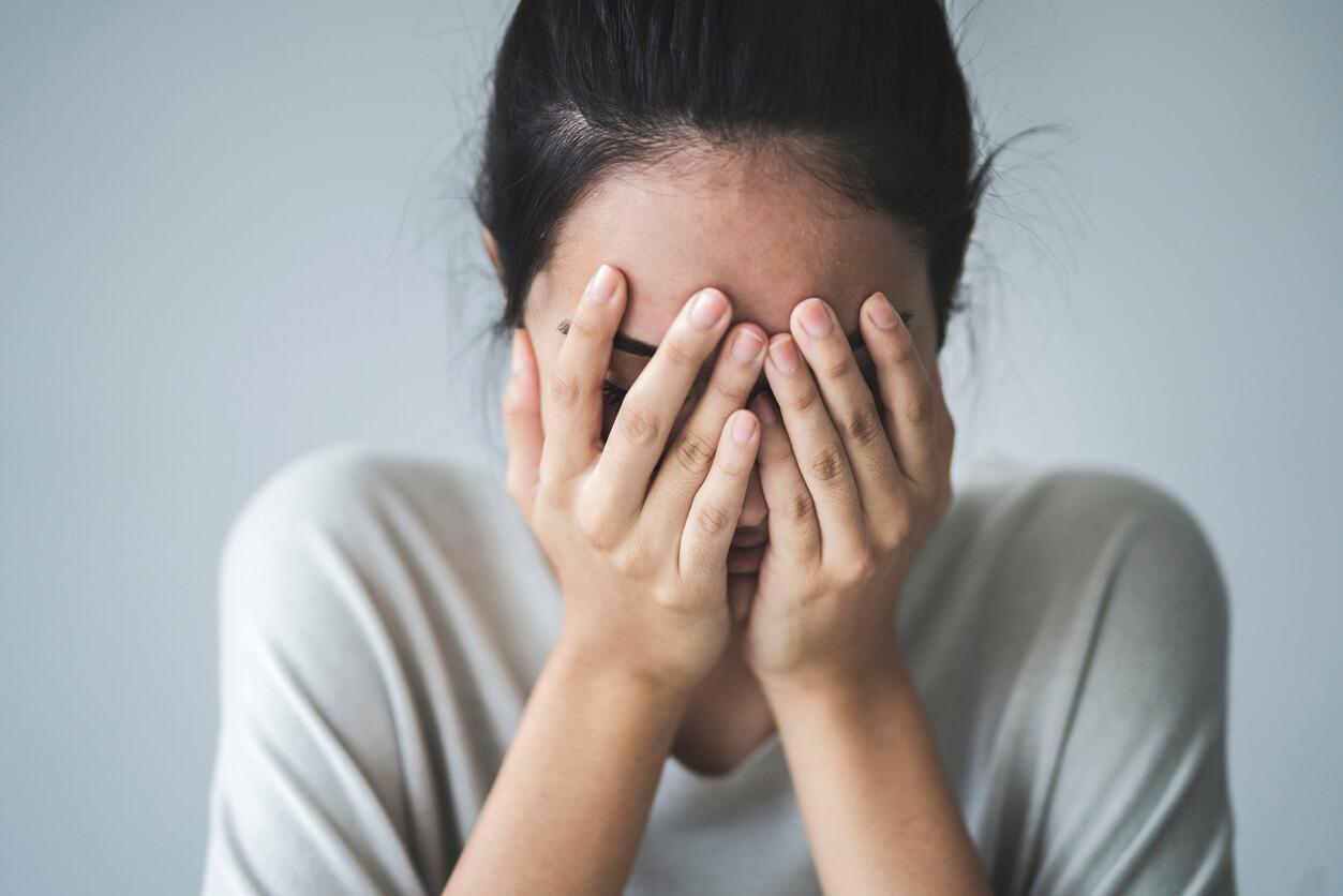 A young girl covering her face with her hands.