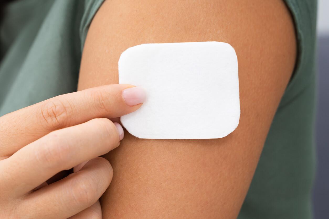 Woman applying a transdermal patch on her arm.