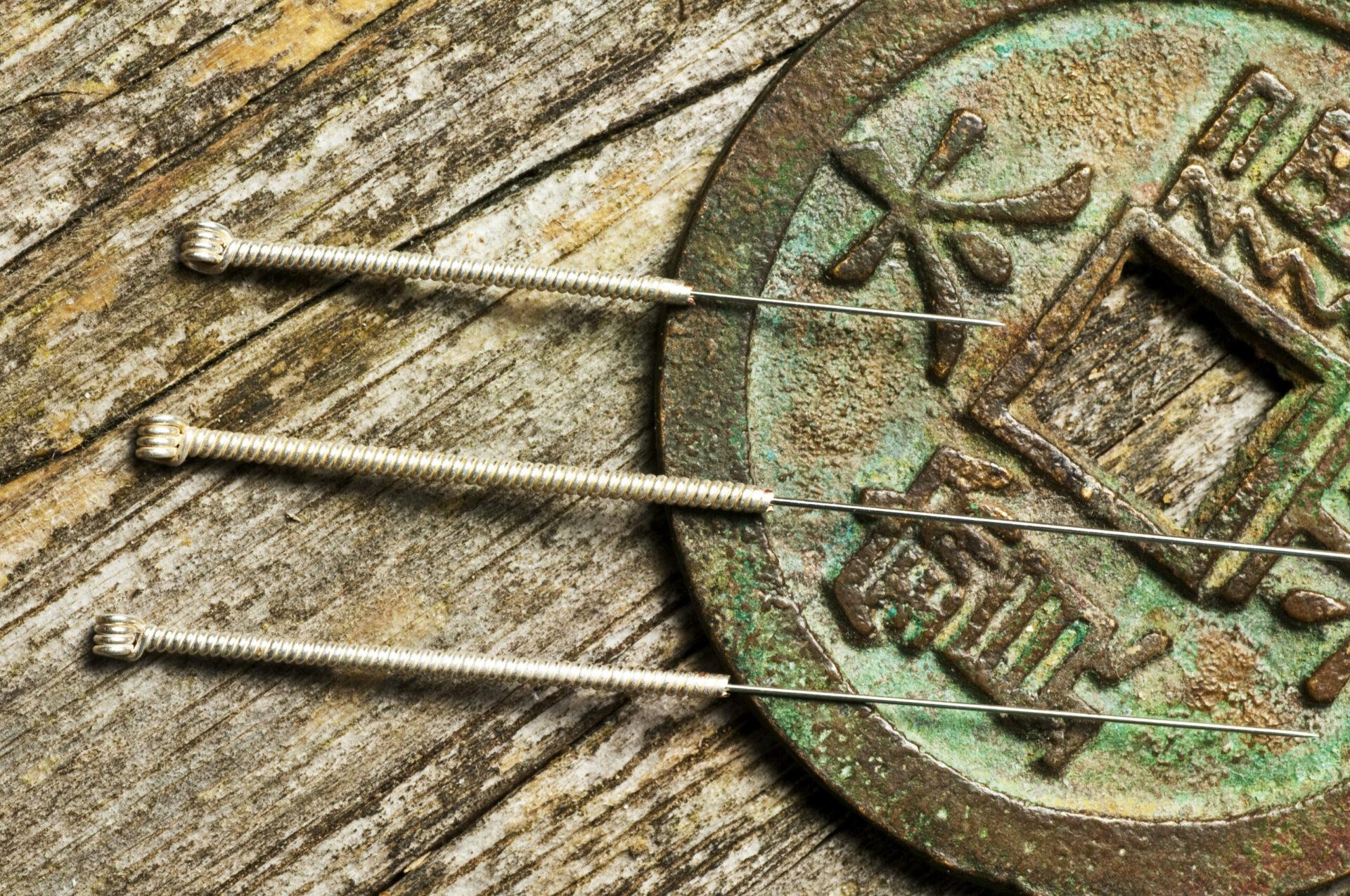Acupuncture needles on a wooden board and a Chinese symbol