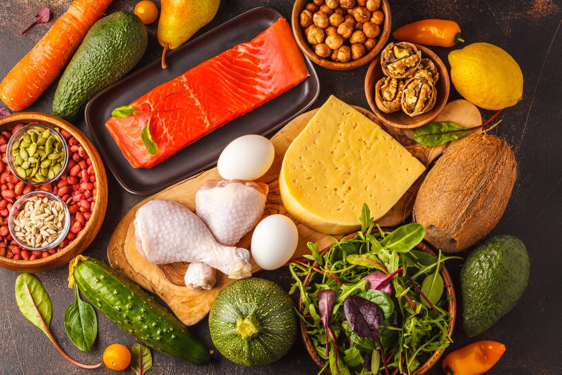 Vegetables, fish, meat, cheese and nuts on a dark background.