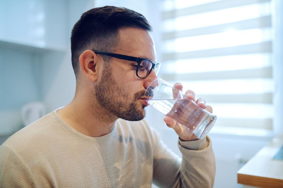 Side view of man sitting and drinking water.