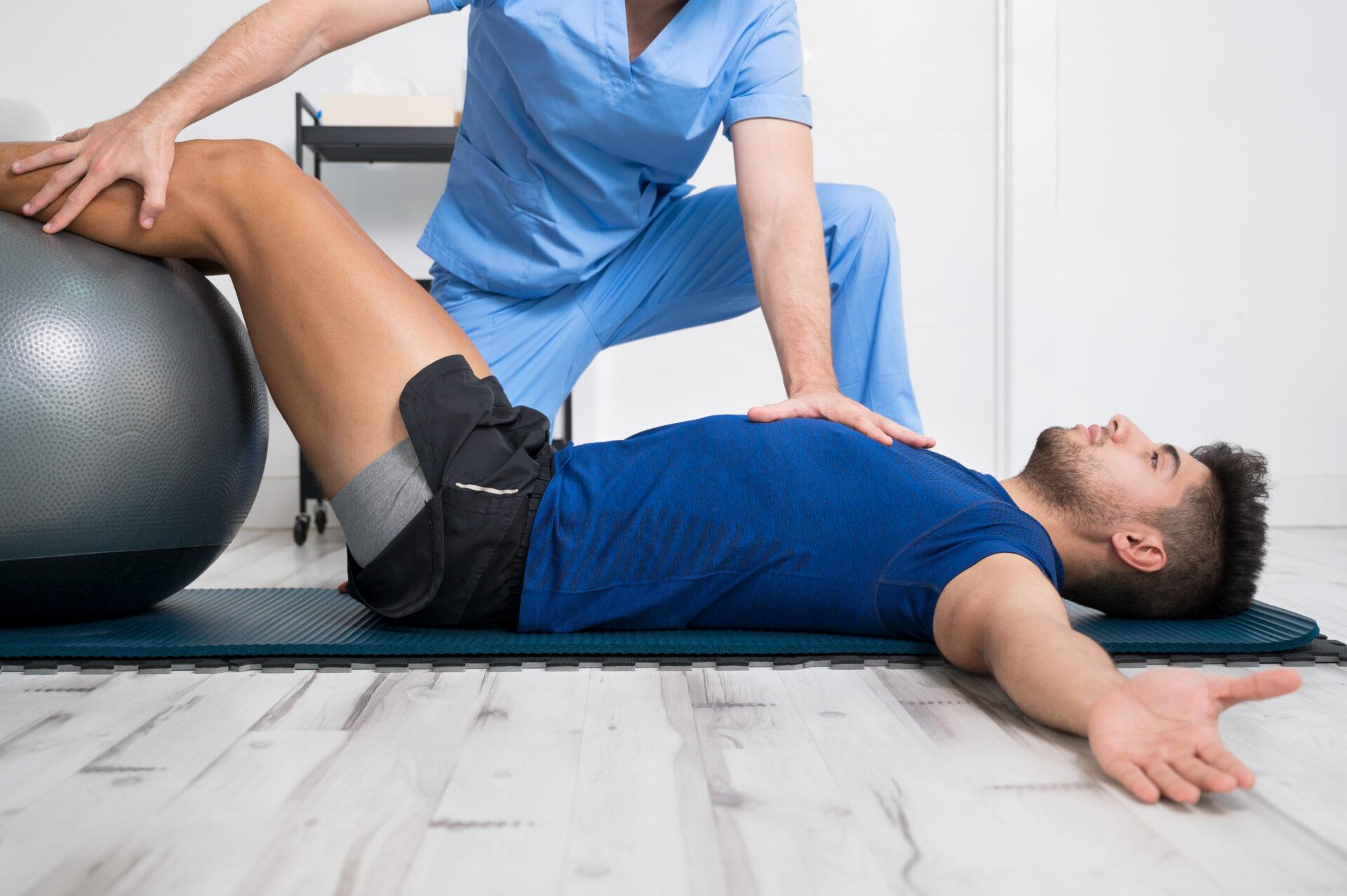 Physiotherapist helps young patient with pilates exercises.