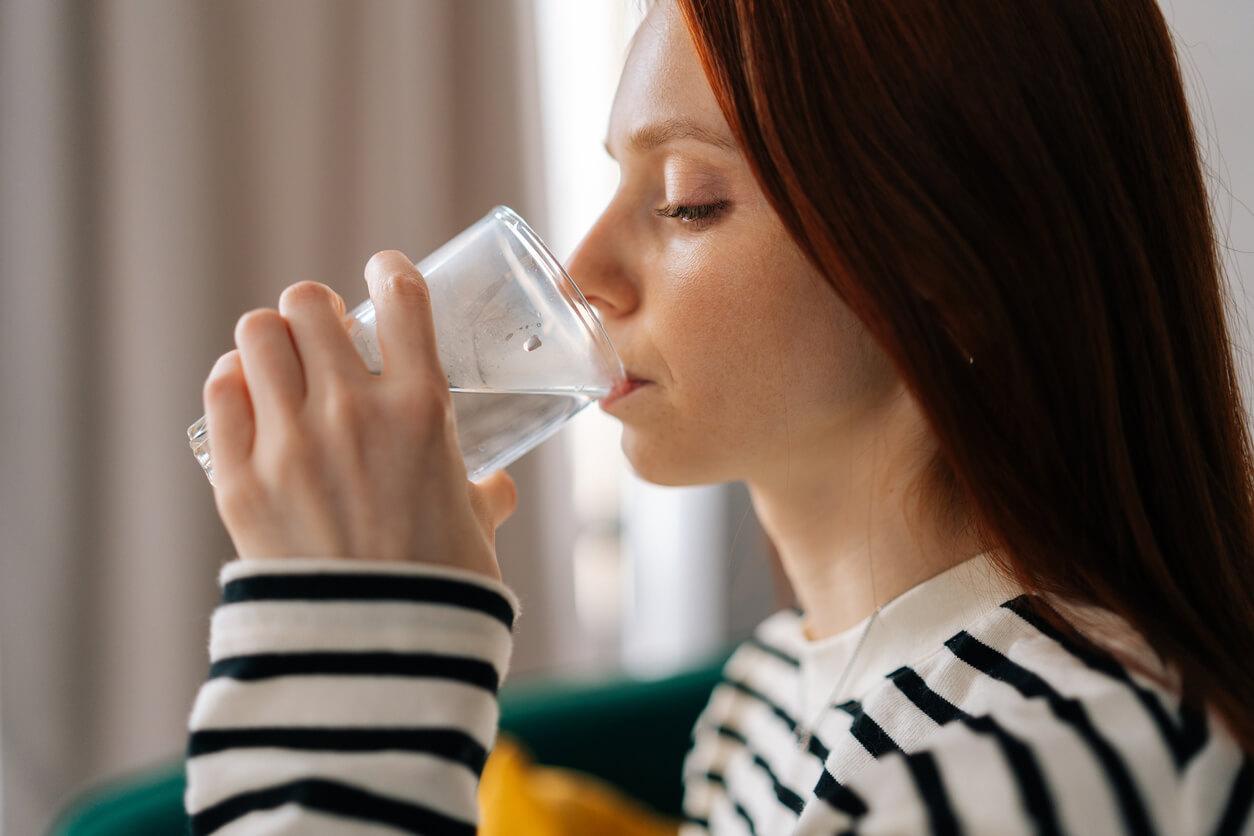 A close-up of a woman drinking still water in the comfort of her home.