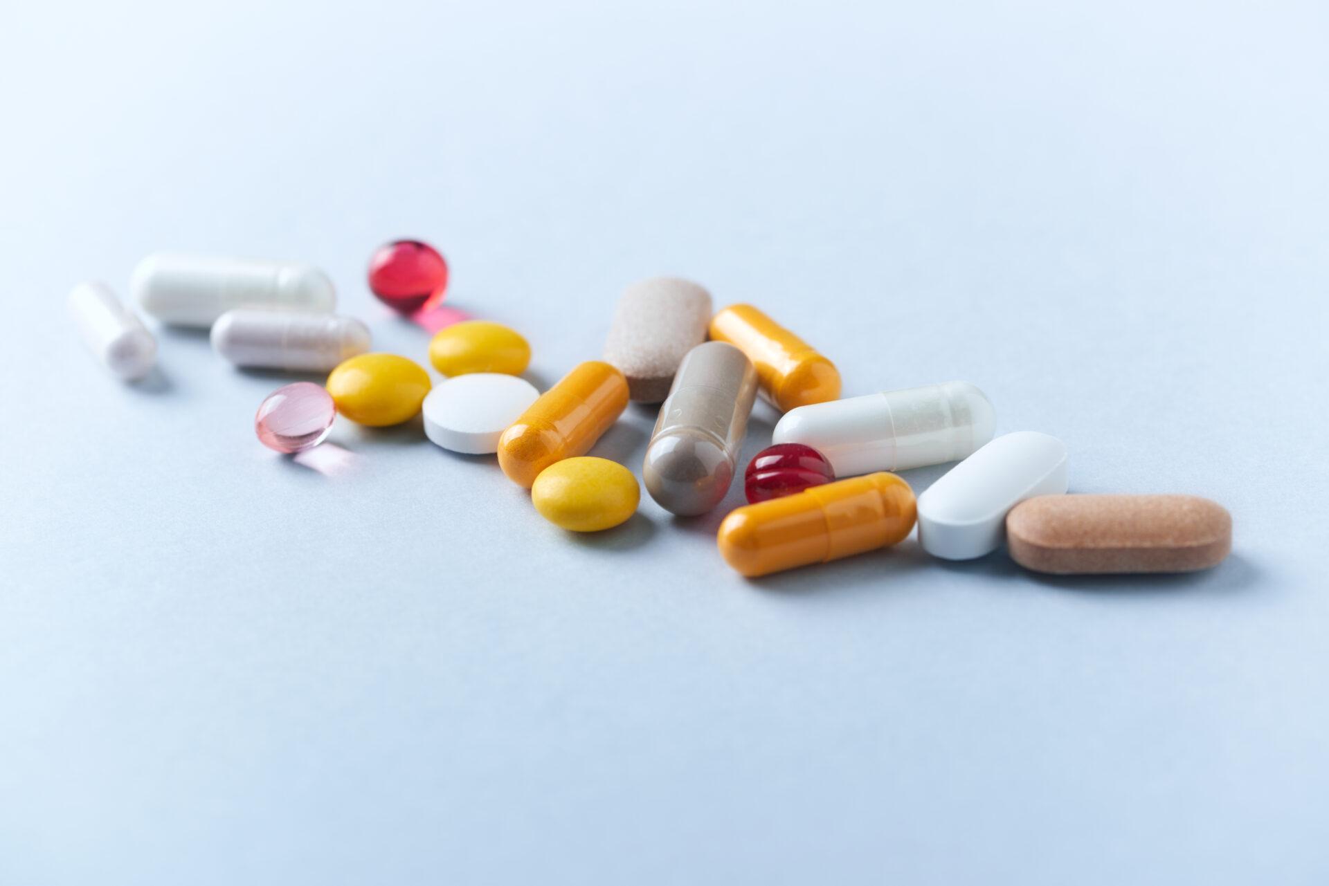 Multicolor vitamins and supplements on bright paper background.