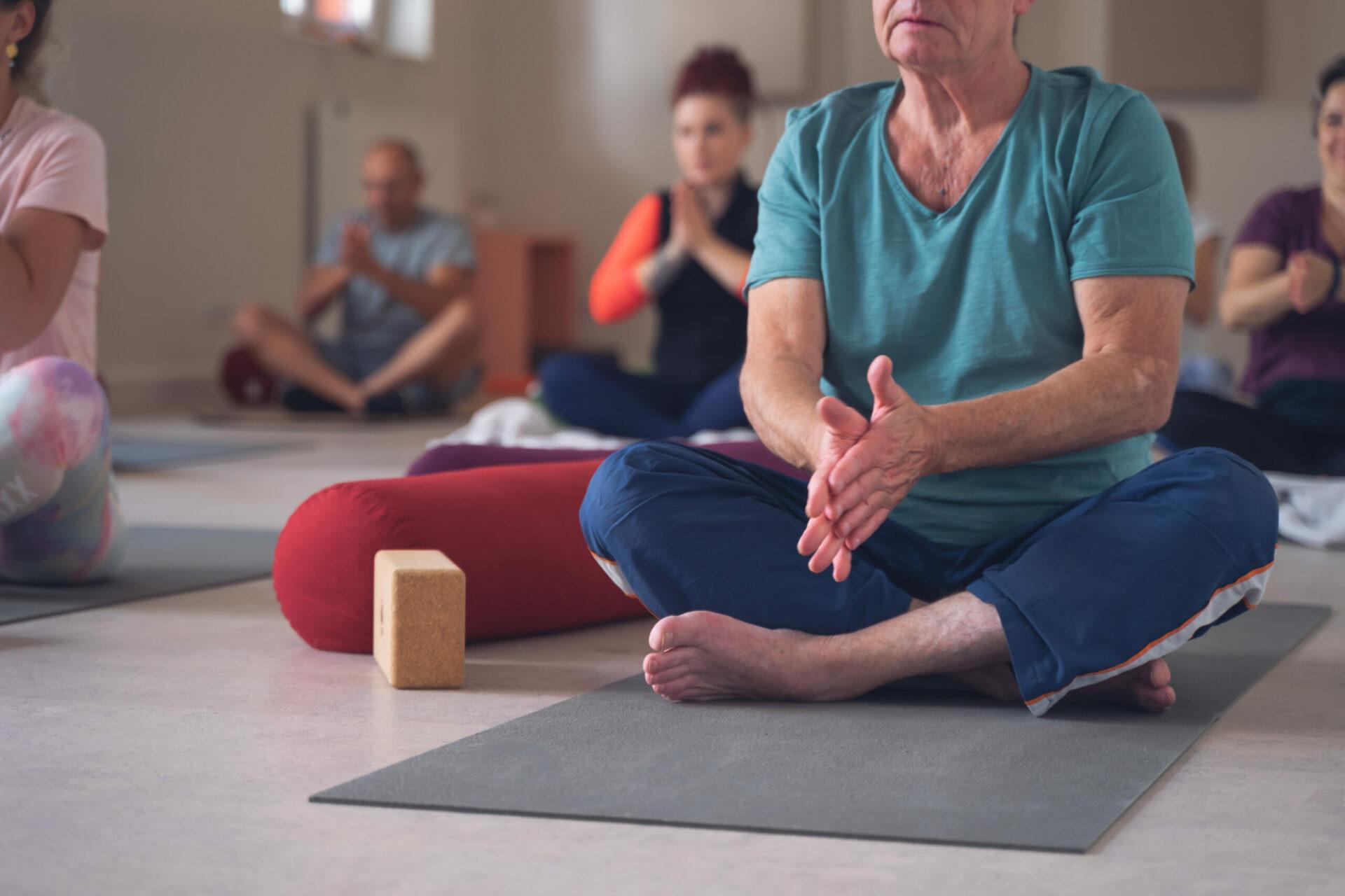 Group of different ages in a yoga class, rubbing their hands together before beginning practice