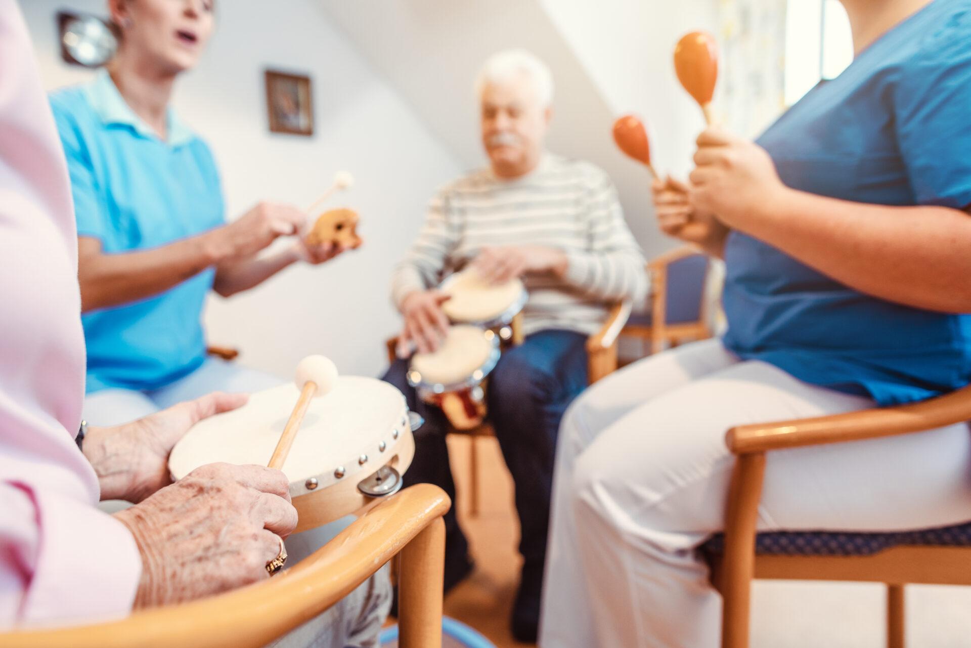 Seniors in nursing home making music with rhythm instruments.