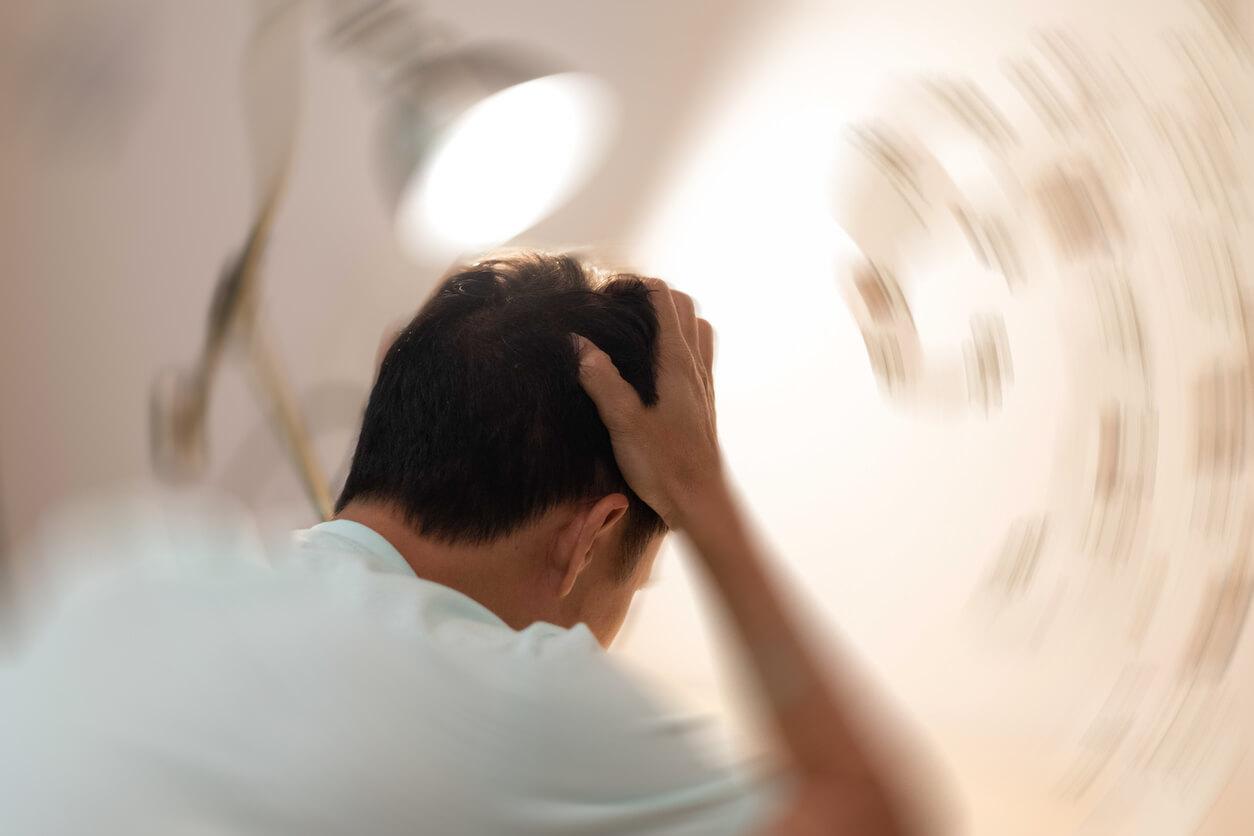 A person holding their head, experiencing dizziness or disorientation from a cannabis high, with the background appearing blurred to indicate a spinning sensation.
